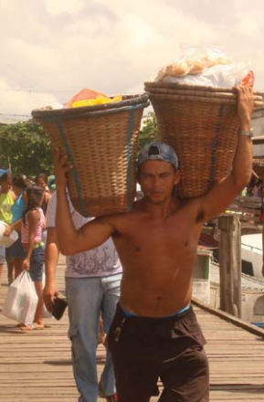 Homem carrega cestos no cais. Acervo dos autores.